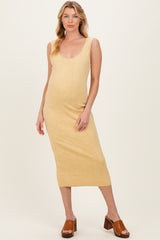 woman wearing a light yellow maternity dress with a scoop neckline and a fitted silhouette, showing her baby bump