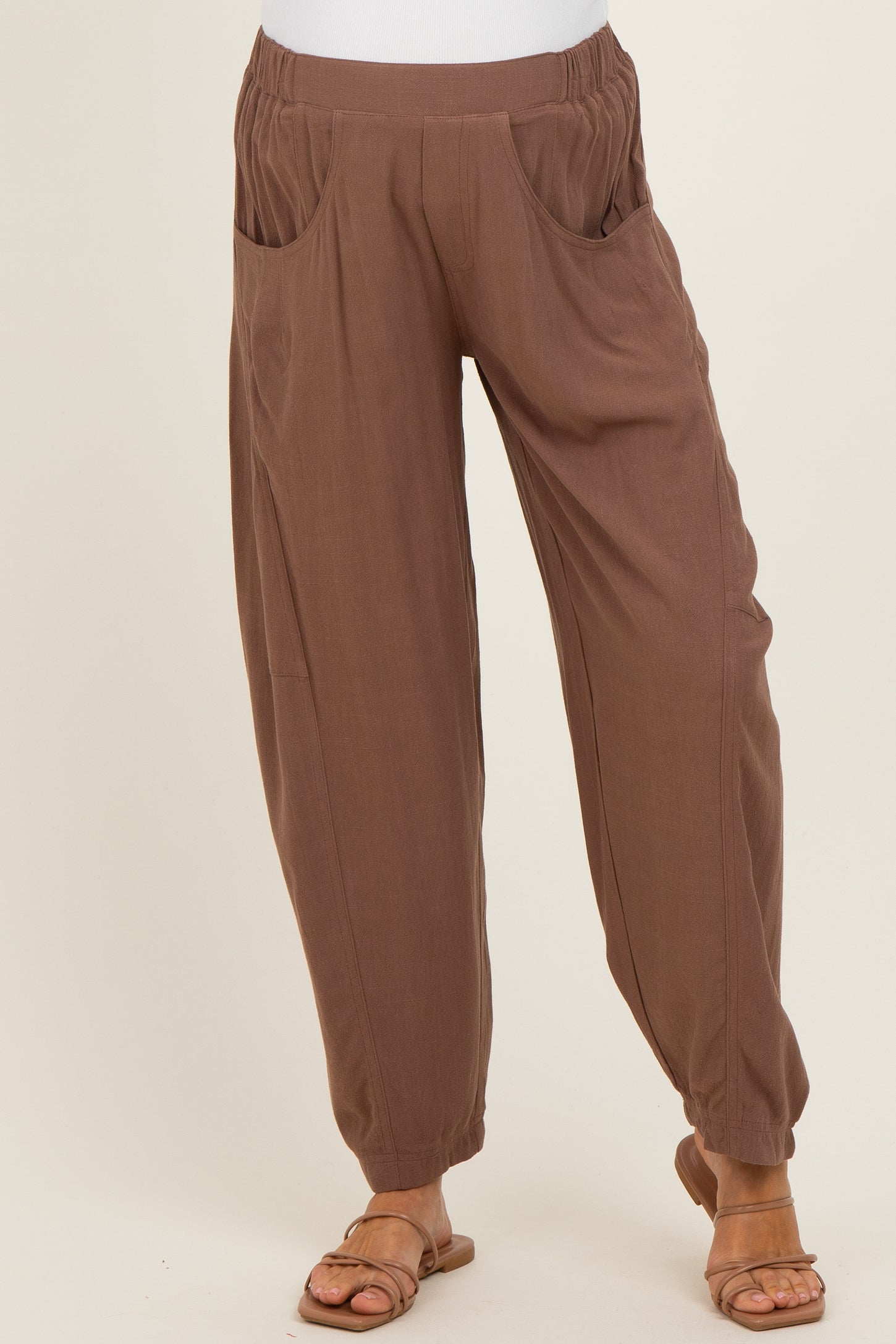 woman wearing brown maternity pants with a relaxed fit and side pockets