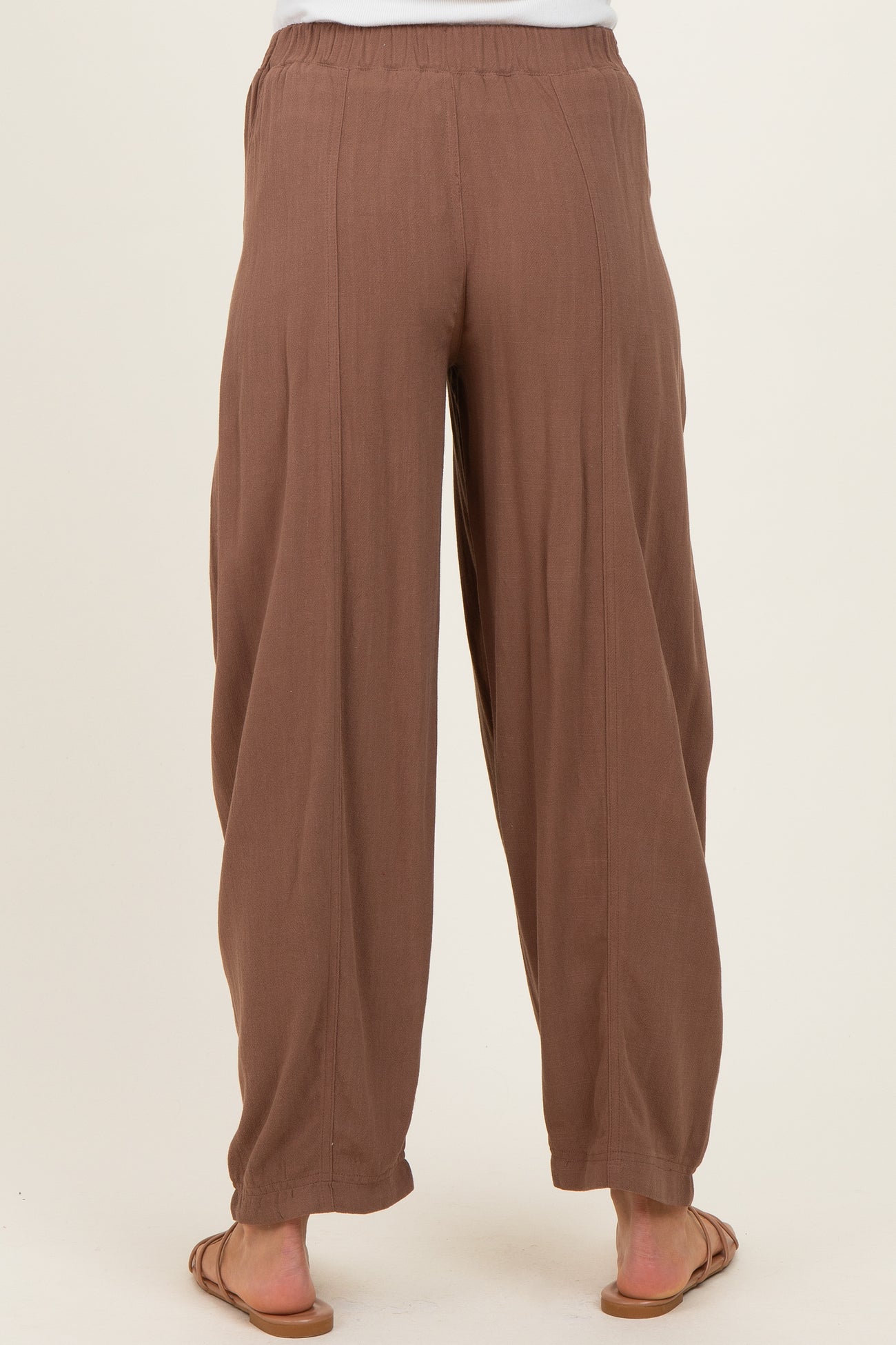 woman wearing brown maternity wide-leg pants, visible elastic waistband and relaxed fit from the back