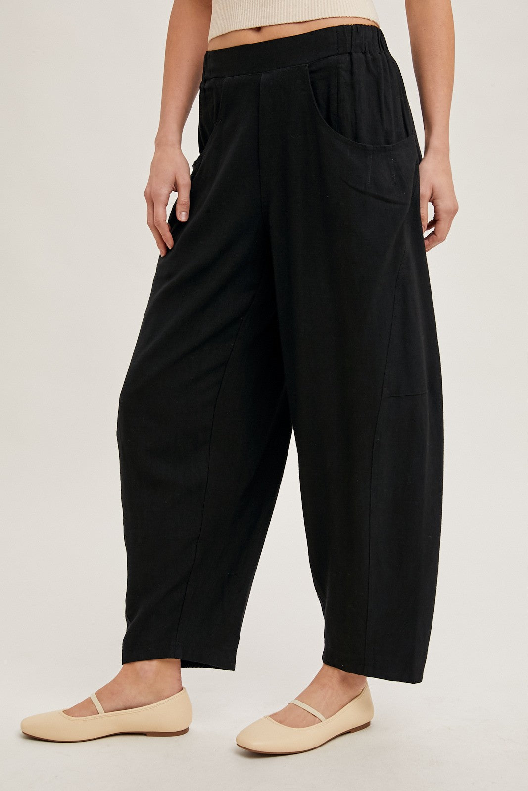 woman wearing black wide-leg pants with a relaxed fit and side pockets, paired with light-colored flats