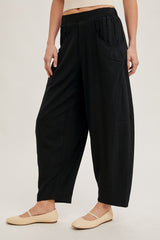 woman wearing black wide-leg pants with a relaxed fit and side pockets, paired with light-colored flats