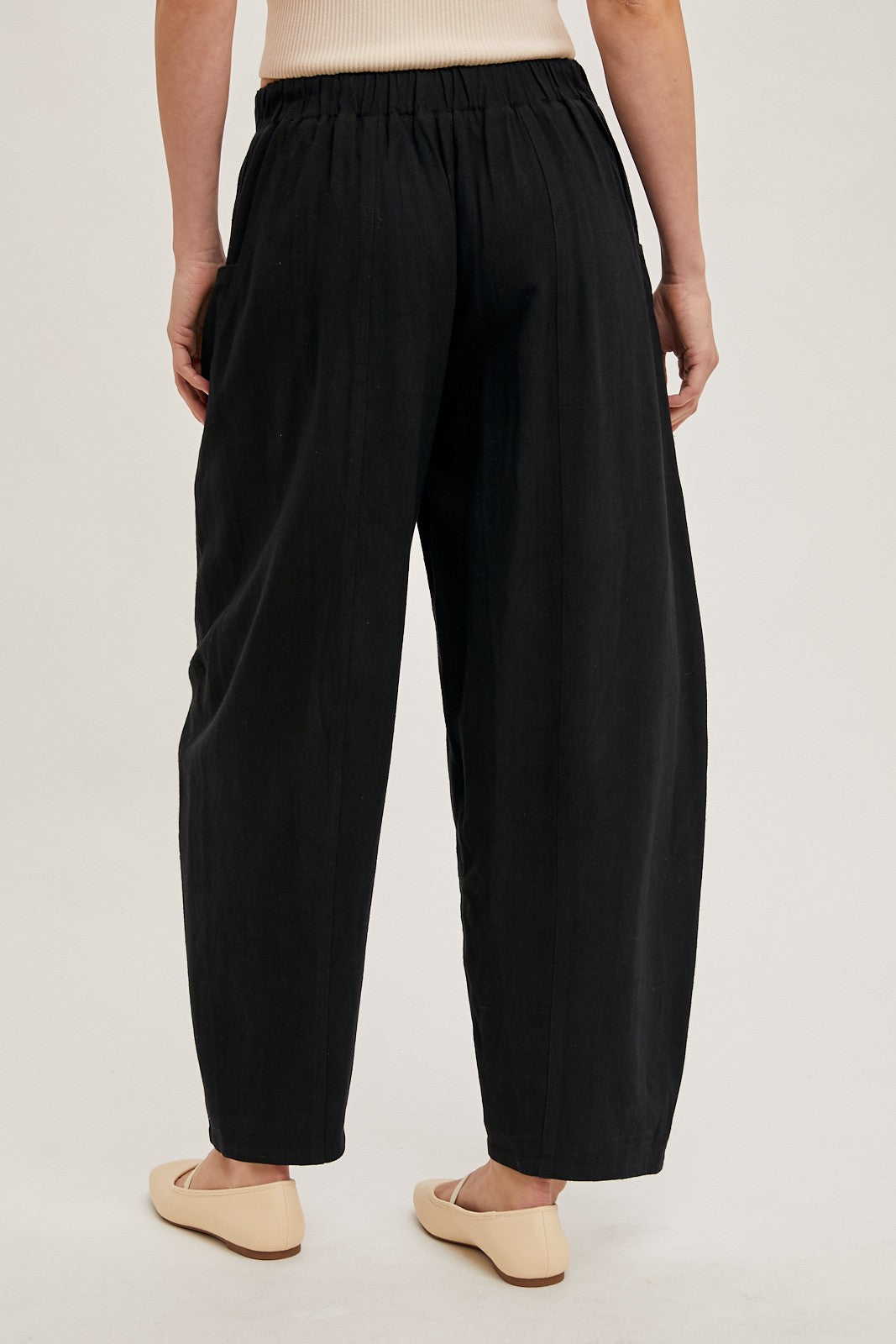 woman wearing black relaxed fit trousers with an elastic waistband and flat front, showing the back view