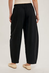 woman wearing black relaxed fit trousers with an elastic waistband and flat front, showing the back view
