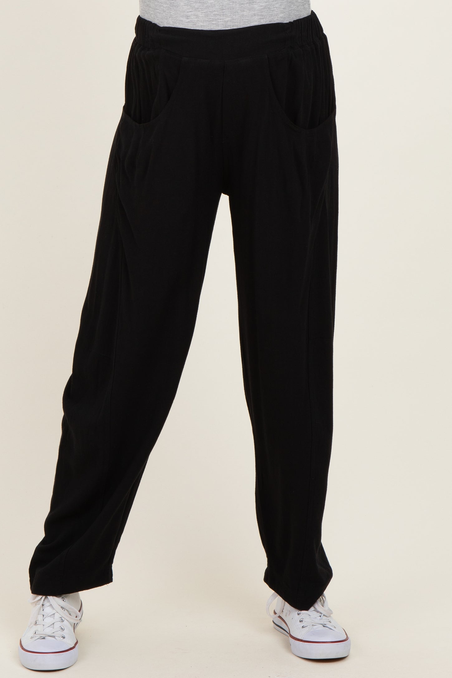 black maternity pants with side pockets and a relaxed fit, model wearing them with a grey top and white sneakers