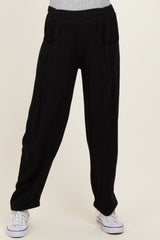 black maternity pants with side pockets and a relaxed fit, model wearing them with a grey top and white sneakers