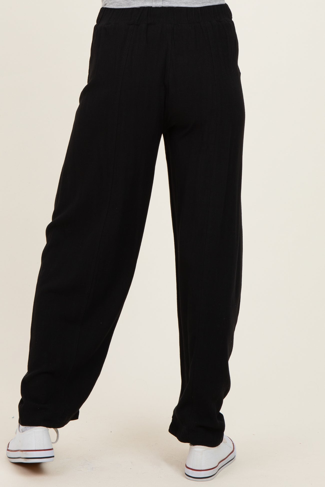woman wearing black maternity pants with a relaxed fit and elastic waistband, viewed from the back