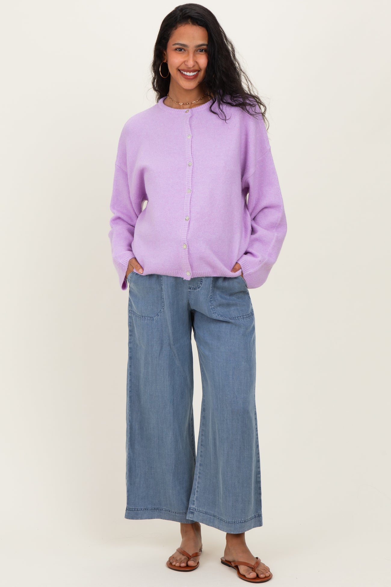 woman wearing a lilac maternity cardigan with buttons and relaxed blue wide-leg jeans