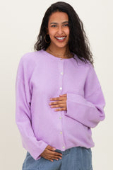 woman wearing a light purple maternity cardigan and holding her baby bump