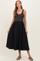 woman wearing a striped black and gold maternity dress with a flowing black skirt and sandals, showcasing her baby bump