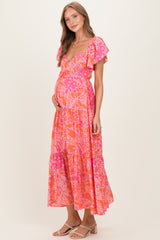 woman wearing a vibrant pink floral maternity maxi dress with ruffle sleeves and a visible baby bump