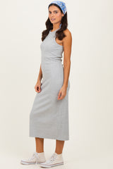 woman wearing a gray sleeveless maxi dress with a fitted silhouette and white sneakers, styled with a headband
