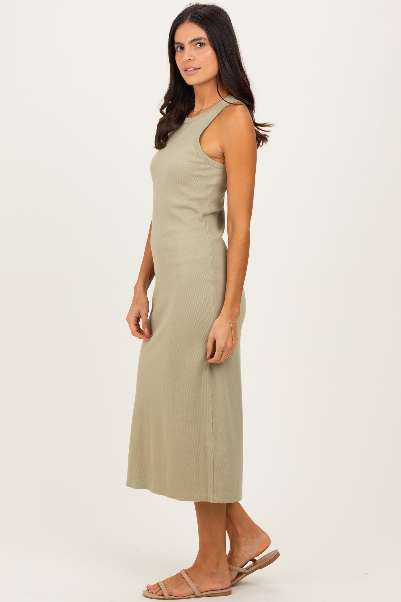 woman wearing a light olive green sleeveless maxi dress with a fitted silhouette and side slits