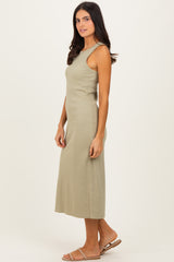 woman wearing a light olive green sleeveless maxi dress with a fitted silhouette and side slits