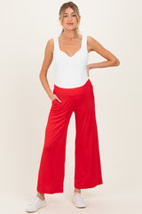 woman wearing a white nursing bodysuit and red wide-leg maternity pants with pockets
