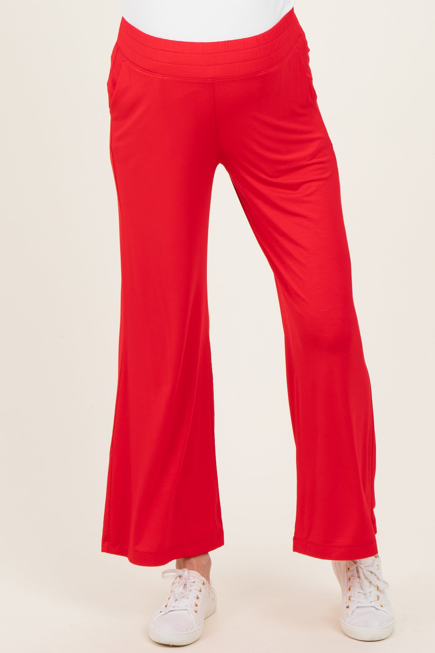 maternity wear in bright red flared pants with pockets, model wearing white sneakers