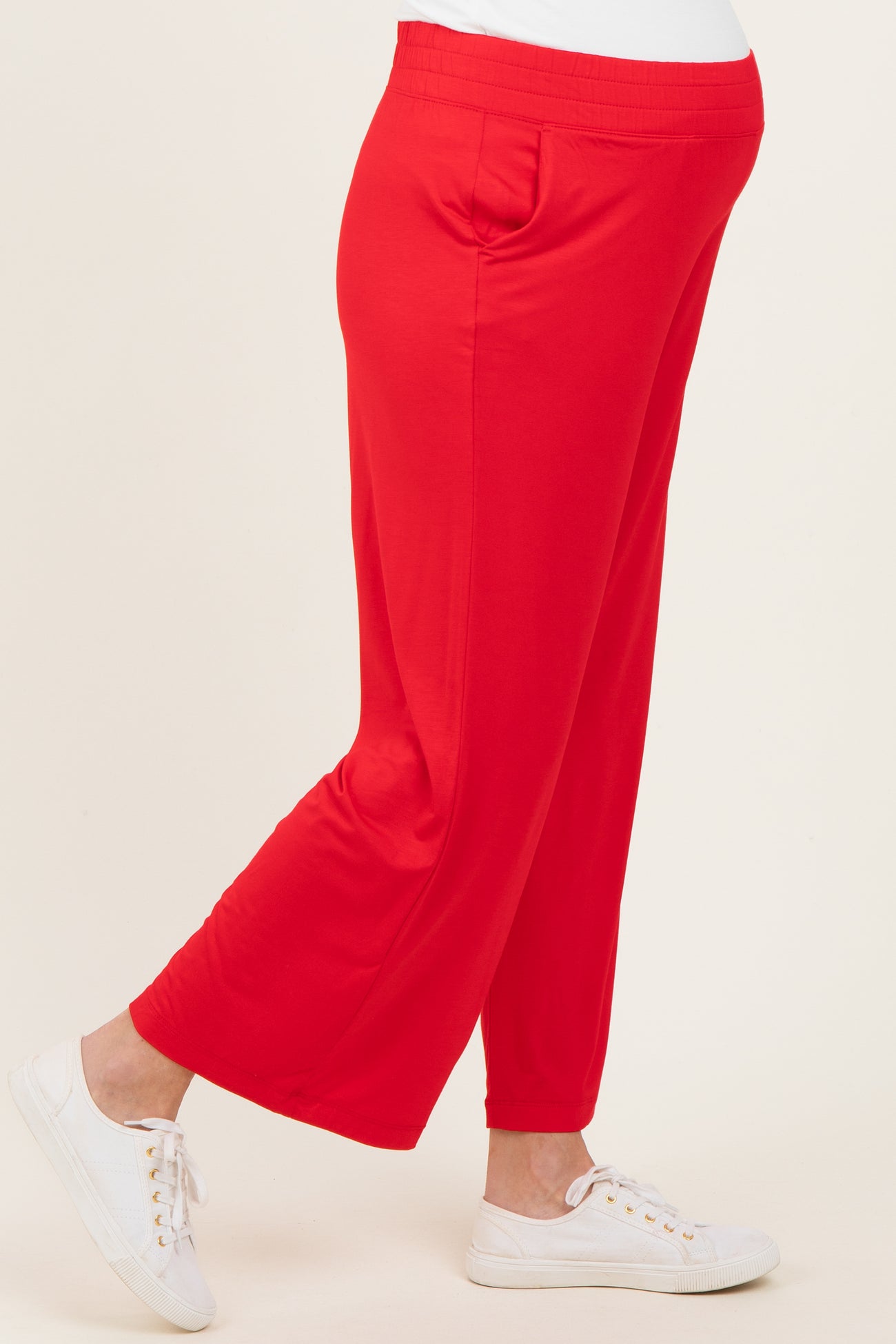 woman wearing bright red maternity pants with side pockets and a comfortable fit, showing her baby bump