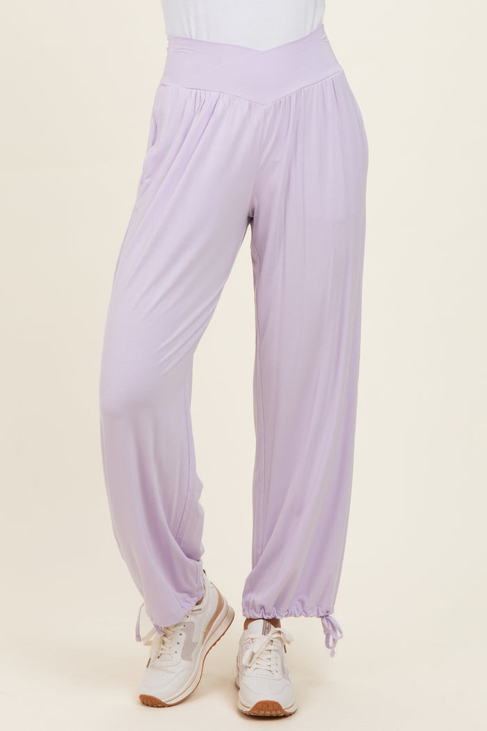 woman wearing lavender casual pants with a high waist and cinched ankle cuffs, paired with white sneakers
