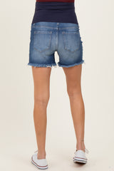 woman wearing maternity denim shorts in a medium wash with frayed hems, showing a smooth waistband and back view