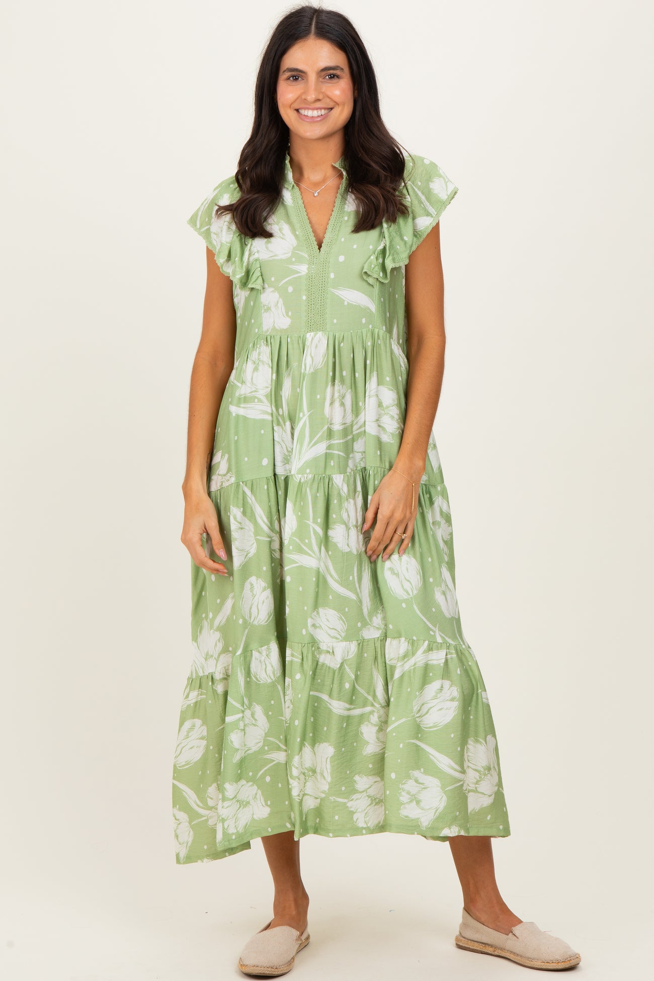 woman wearing a green floral midi dress with ruffle sleeves and a tiered skirt