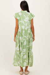 woman wearing a light green floral maxi dress with ruffled sleeves and a tiered skirt, facing away from the camera