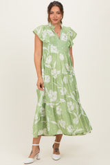woman wearing a green floral maternity maxi dress with flutter sleeves and tiered design, showcasing her baby bump