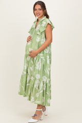 woman wearing a green floral maternity maxi dress with ruffled sleeves and holding her baby bump