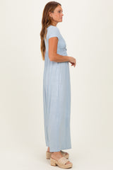 woman wearing a light blue short sleeve maxi dress with a knotted detail, standing sideways