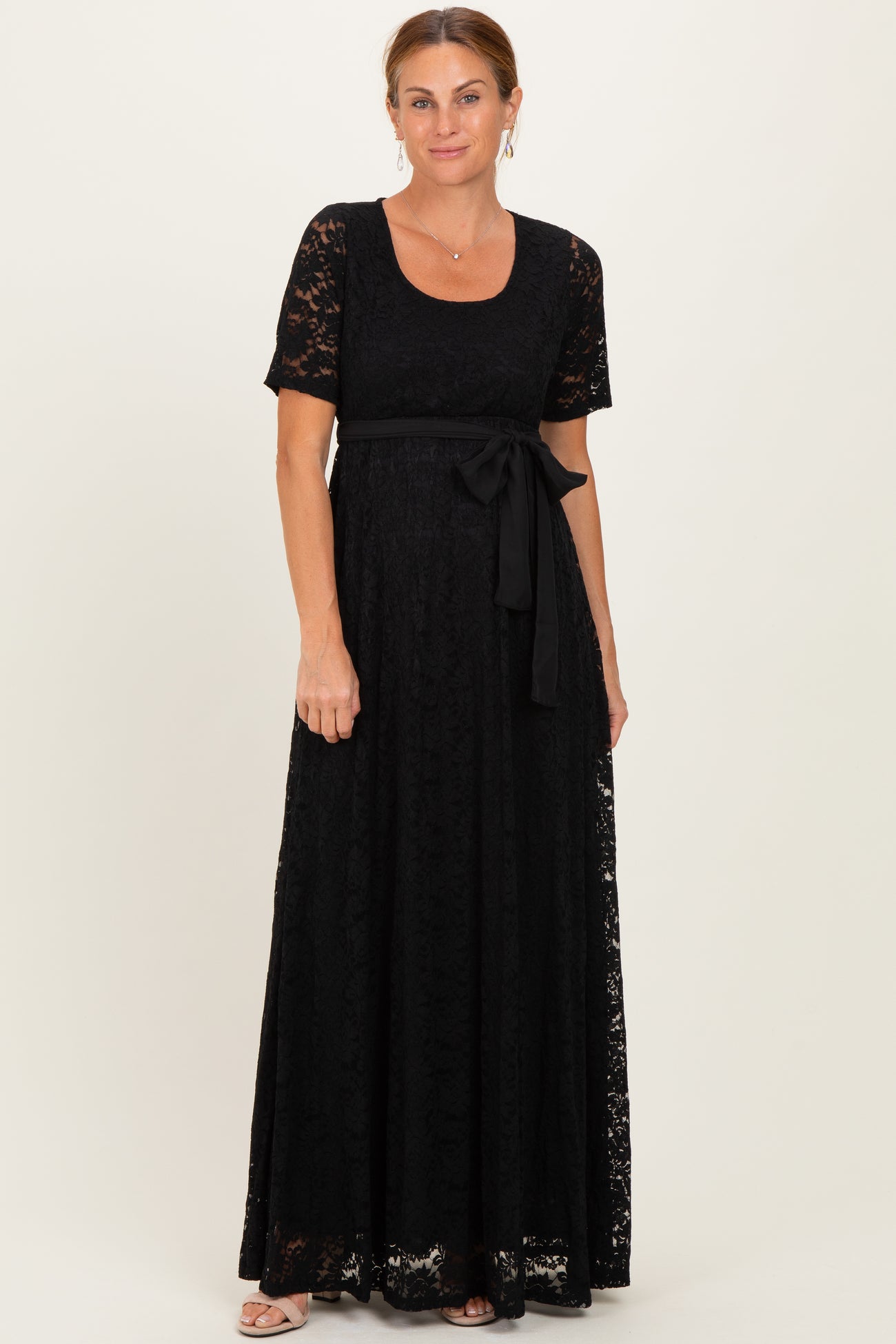 woman wearing a black lace maxi dress with short sleeves and a tie belt at the waist