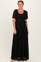 woman wearing a black lace maxi dress with short sleeves and a tie belt at the waist