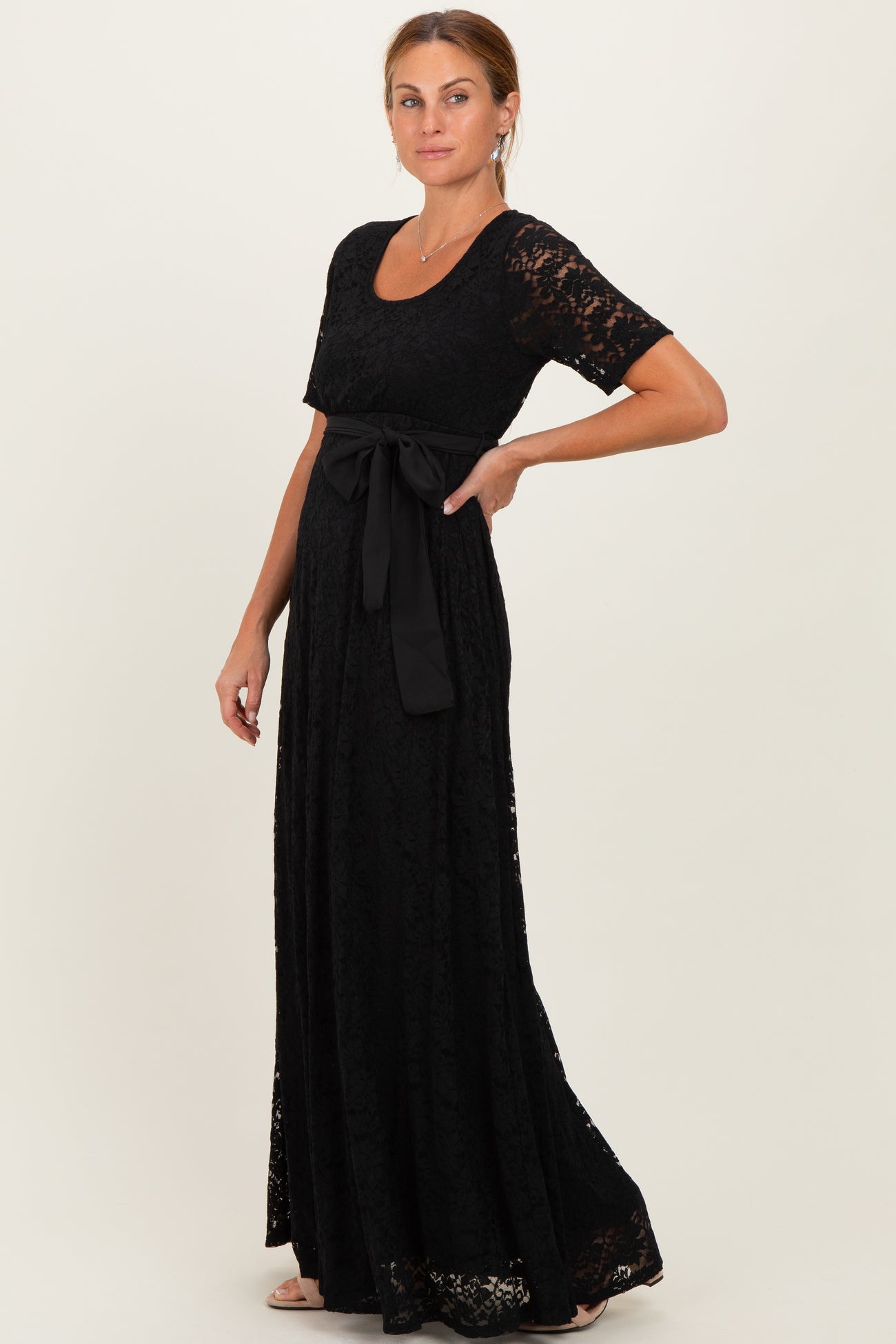 woman wearing a black lace maxi dress with a scoop neckline and a tied waist detail