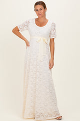 woman wearing a cream lace maxi dress with a short sleeve and a satin waist tie