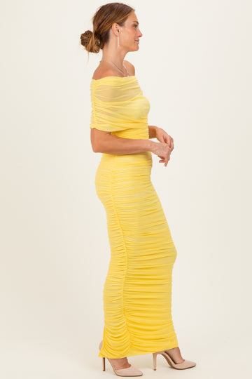 woman wearing a yellow off-the-shoulder ruched maxi dress with fitted silhouette and sheer details