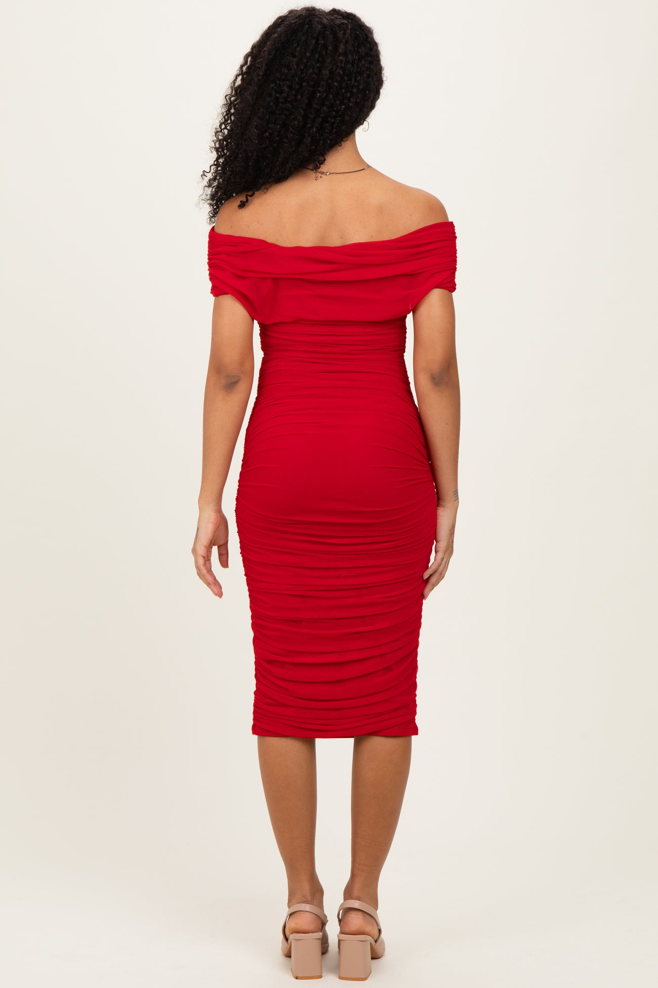 woman wearing a red off-the-shoulder fitted midi dress with ruching details, viewed from the back