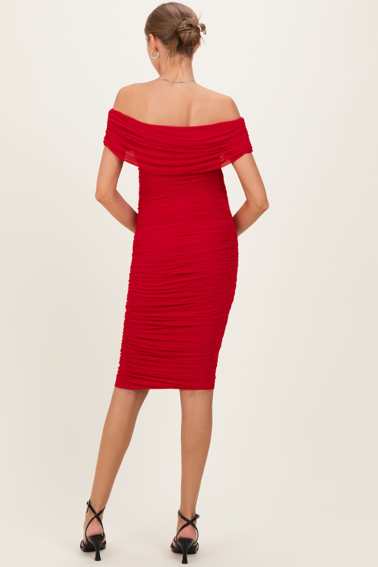 woman wearing a red off-the-shoulder ruched maternity dress, showing a fitted silhouette from the back