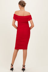 woman wearing a red off-the-shoulder ruched maternity dress, showing a fitted silhouette from the back