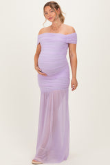 woman wearing a light purple off-the-shoulder maternity gown with ruching and a flowing skirt, holding her baby bump