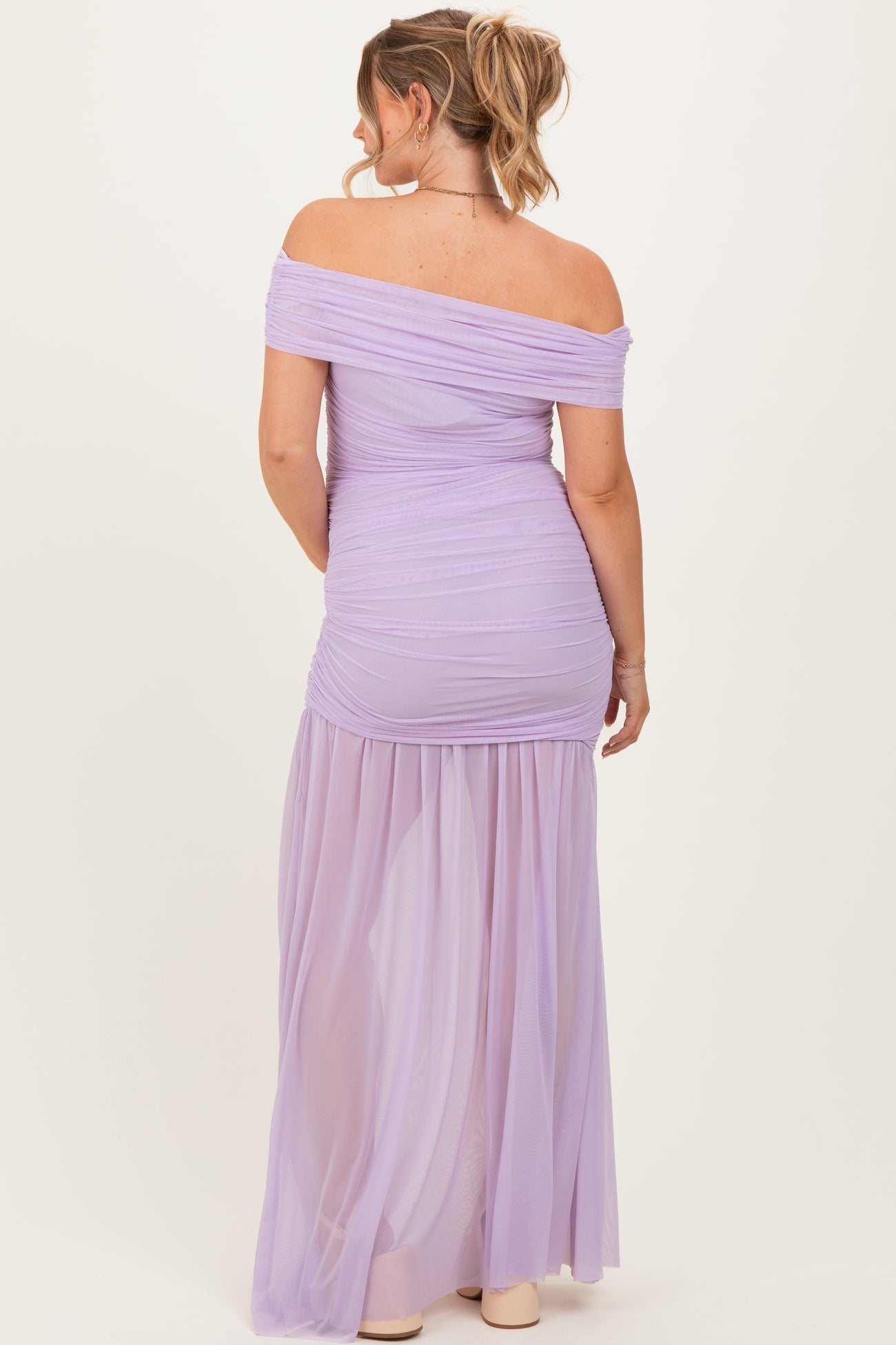 woman wearing a lilac off-the-shoulder maternity dress with ruched detailing and a flowy skirt, showing her baby bump