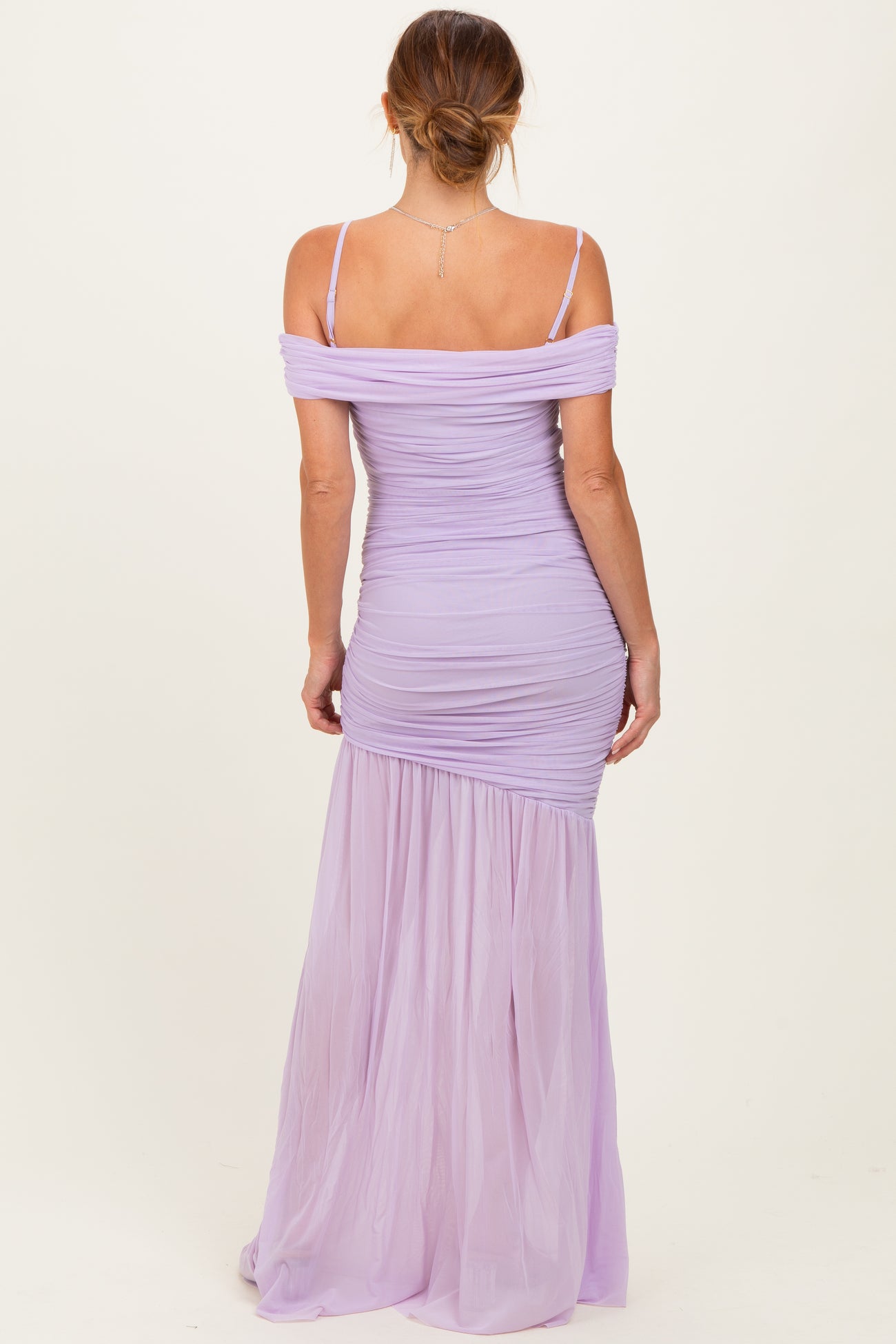 woman wearing a lavender off-the-shoulder ruched maxi dress with a flowing skirt and fitted bodice