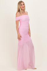woman wearing a pink off-the-shoulder ruched maxi dress with a sheer skirt