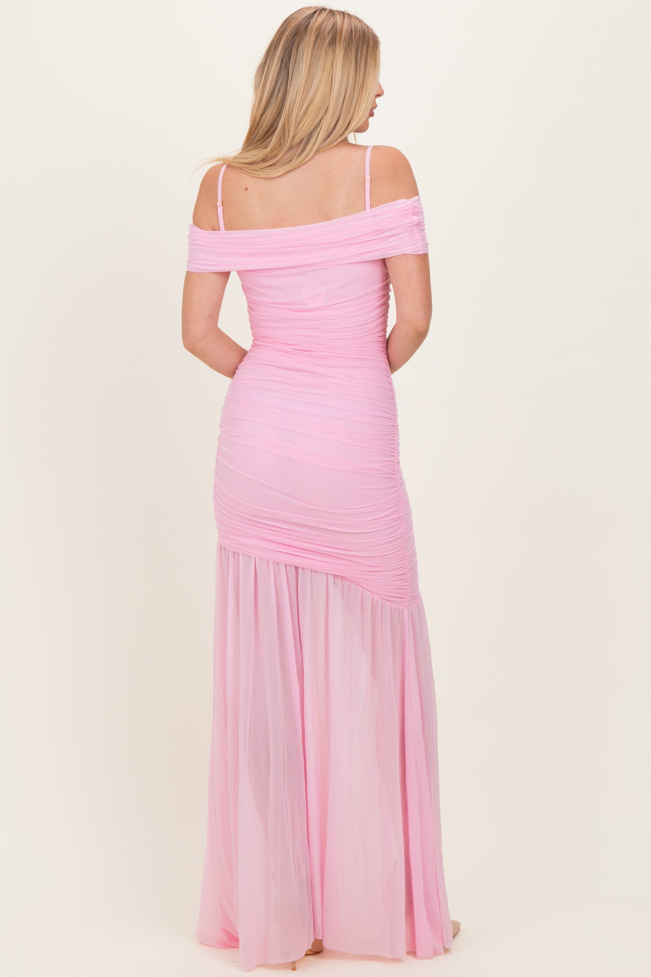 woman wearing a pink off-the-shoulder ruched maxi dress with a sheer skirt from the back