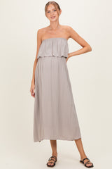 woman wearing a light grey strapless maternity dress with a ruffled overlay and a flowing silhouette