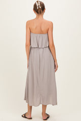 woman wearing a gray strapless maternity maxi dress with a layered ruffle detail, showing her back
