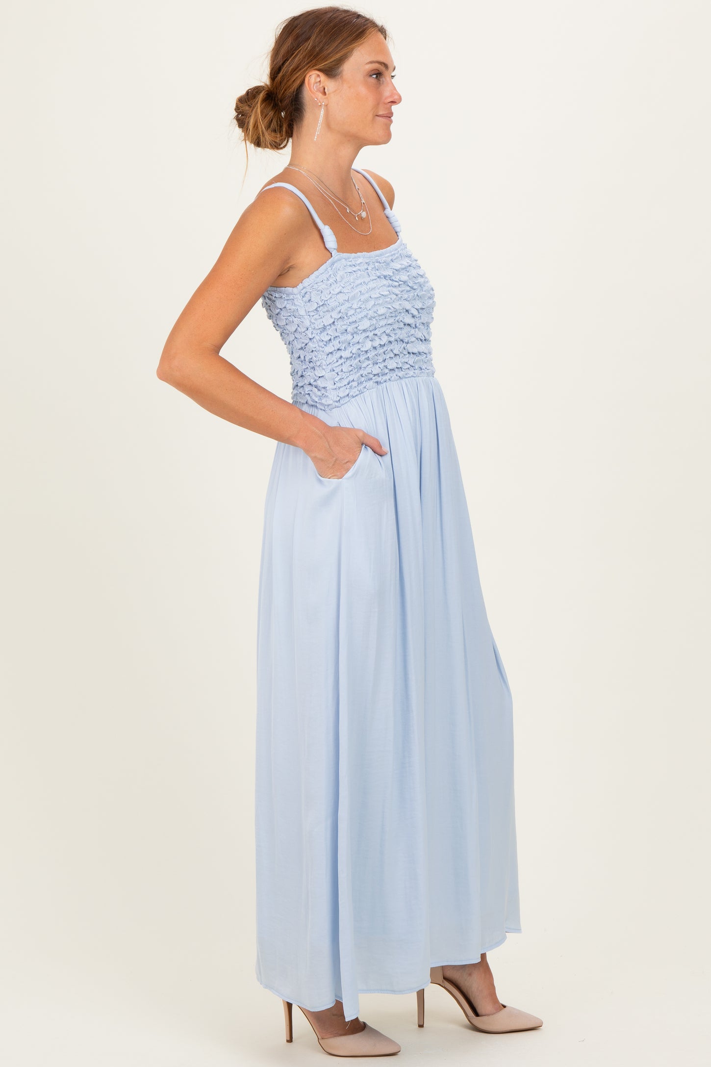 woman wearing a light blue maxi dress with a smocked bodice and pockets, standing in a side view