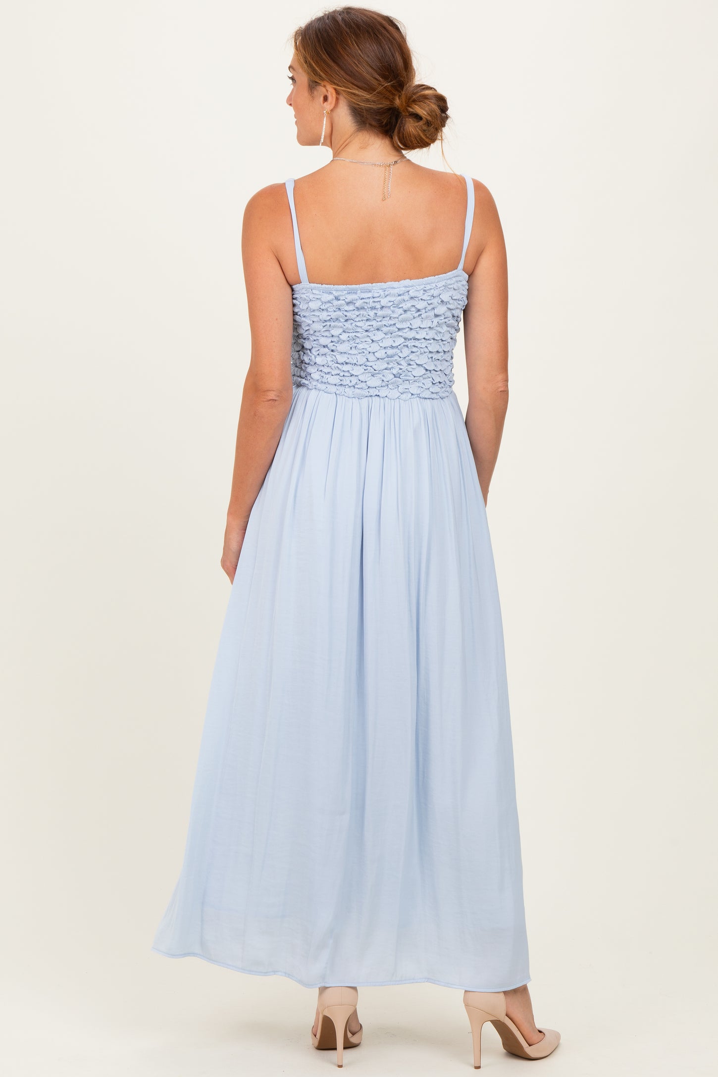 woman wearing a light blue maxi dress with a smocked bodice and spaghetti straps, photographed from the back