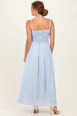 woman wearing a light blue maxi dress with a smocked bodice and spaghetti straps, photographed from the back