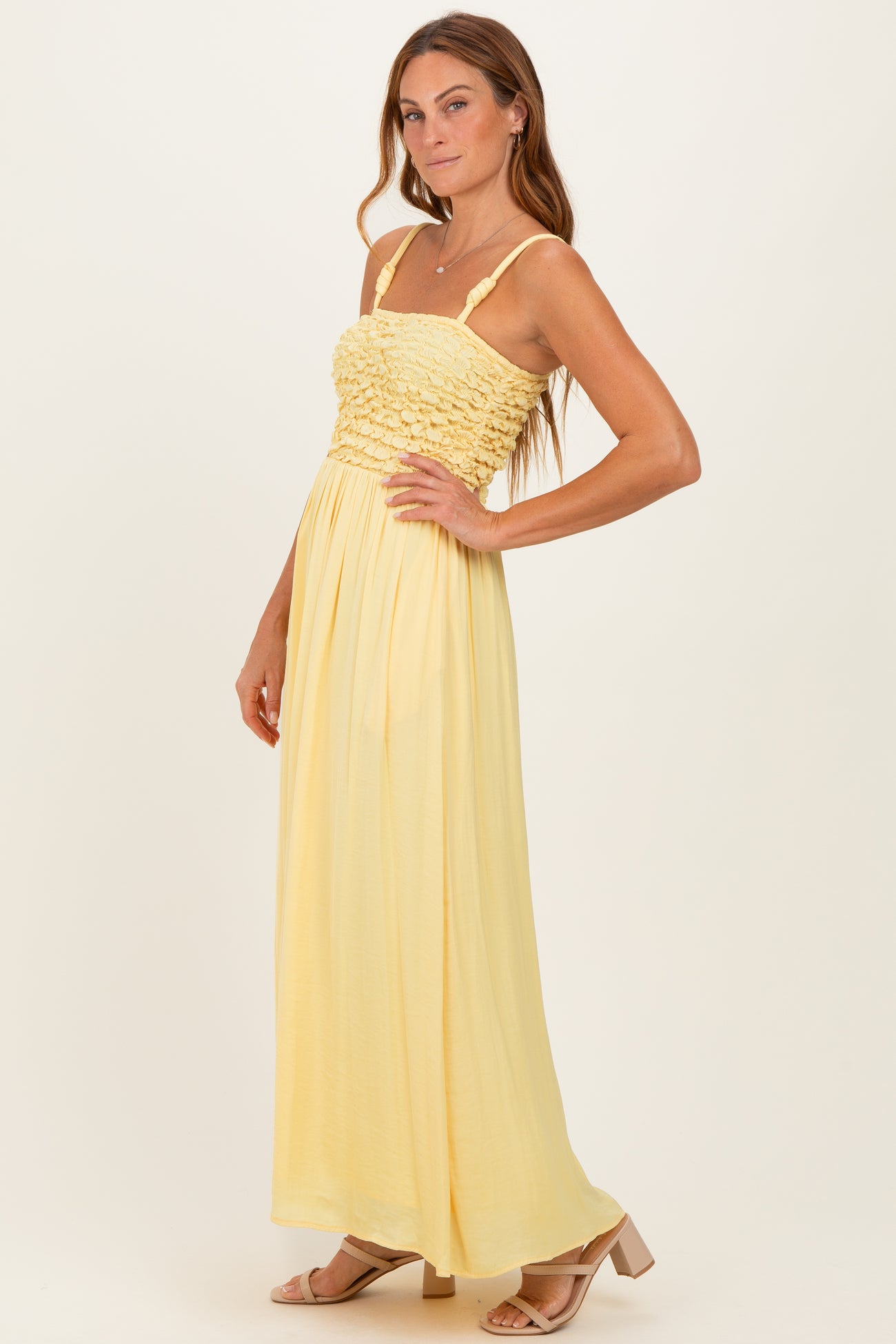 woman wearing a long yellow maxi dress with a smocked bodice and spaghetti straps