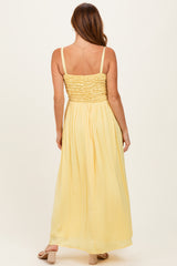 woman wearing a yellow maxi dress with a smocked bodice and flowing skirt, photographed from the back