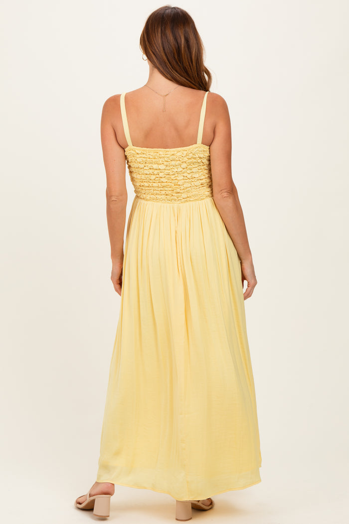 woman wearing a yellow maxi dress with a smocked bodice and flowing skirt, photographed from the back