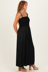 woman wearing a black maxi dress with a fitted ruffled bodice and flowy skirt, standing in profile