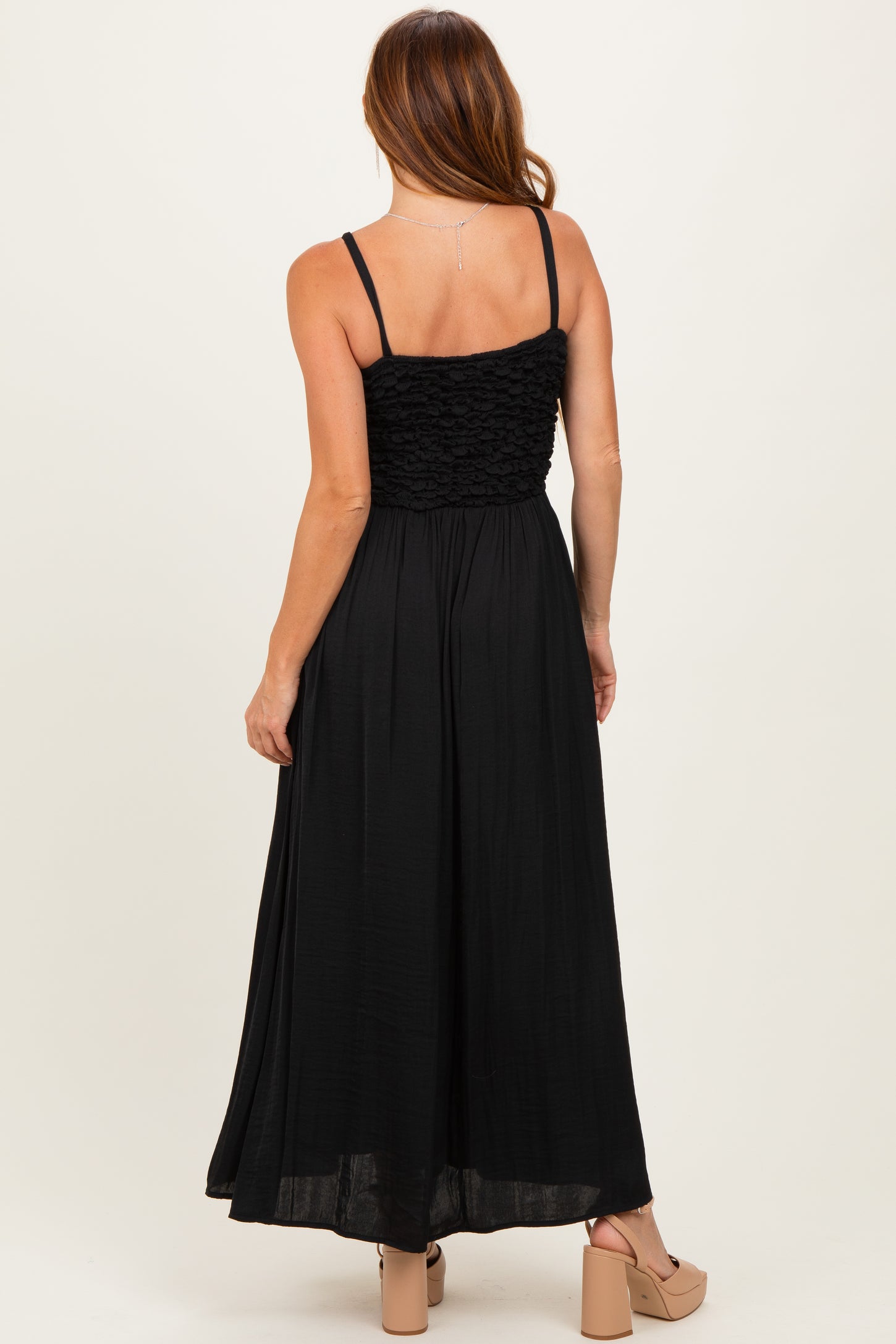 woman wearing a black maxi dress with a smocked bodice and thin straps, view of the back